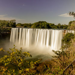 Scenic view of waterfall against sky