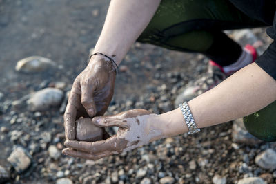 Woman putting mud on hands and face while enjoying outdoors in nature.