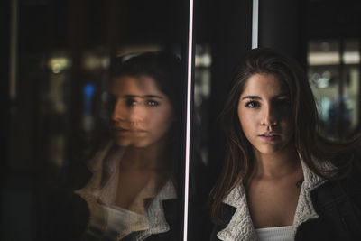 Portrait of young woman by glass window