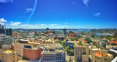 High angle view of buildings in city against blue sky