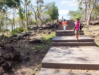 Rear view of people walking on footpath amidst trees