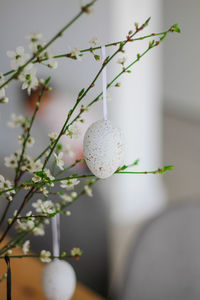 Fresh flowering branches decorated with easter colorful eggs in a vase on a wooden table.