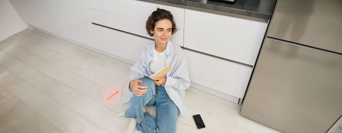 Portrait of young woman standing against wall