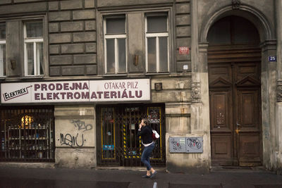 Full length of woman standing by building in city