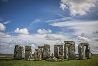 Stonehenge on field against cloudy sky