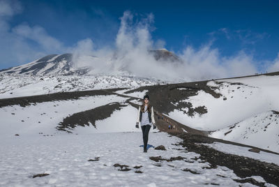 Woman standing on snow covered landscape against sky