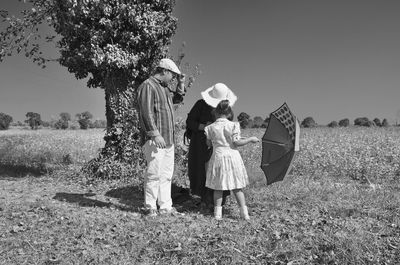 Full length of family with umbrella standing on field