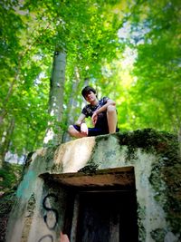 Man sitting on wooden wall in forest