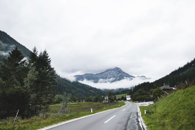 Empty road by mountains against sky