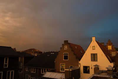 Houses in town against sky at sunset