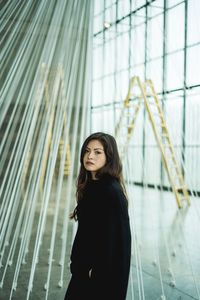 Portrait of young woman standing against wall