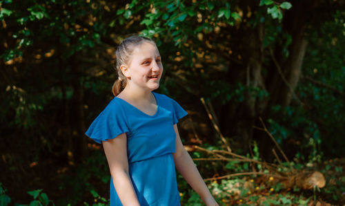 Portrait of young woman standing against plants