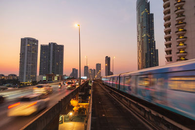 Illuminated city buildings against sky at dusk