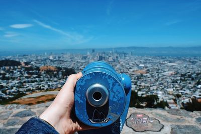 Midsection of man photographing cityscape against blue sky