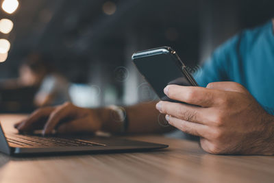 Midsection of woman using mobile phone at table