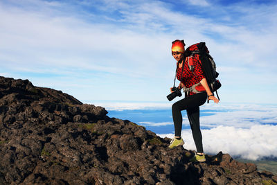 Low angle view of woman standing on rock against sky