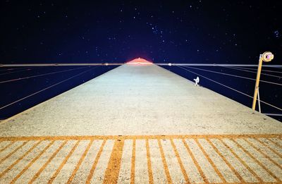 Digital composite image of illuminated railing against sky at night