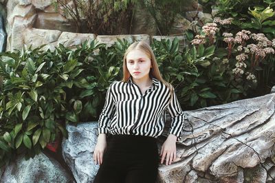 Portrait of young woman standing against plants