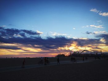 Silhouette people on beach against sky during sunset