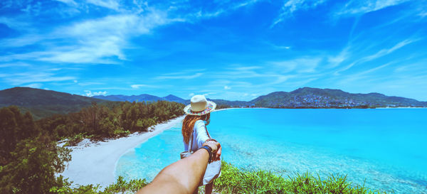 Rear view of woman holding sea against sky