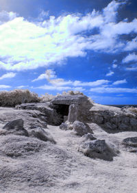 View of rocks on land against cloudy sky