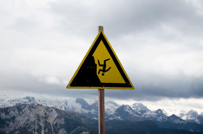 Warning sign on mountains against sky
