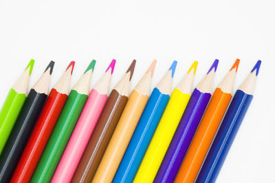 Close-up of colored pencils over white background