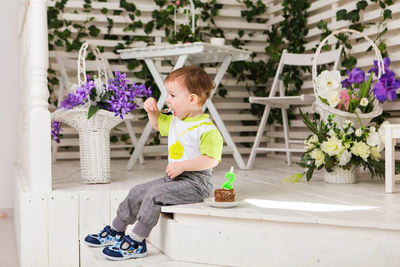 Full length of cute baby sitting on potted plant