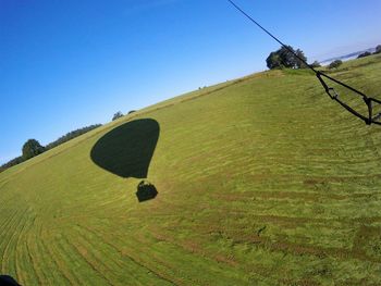 Shadow of hot air balloon on field