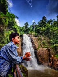 Side view of woman against waterfall