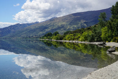 Scenic view of lake by mountains against sky