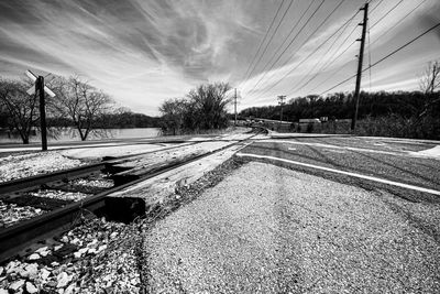 Railroad tracks by road against sky
