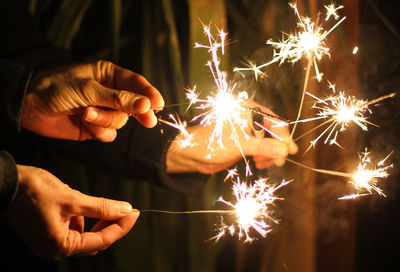 Person hand holding firework display at night