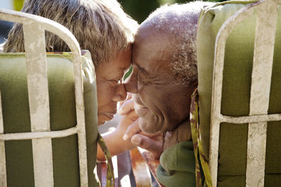 Senior couple rubbing nose while sitting on chairs