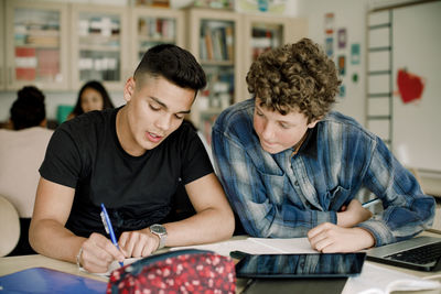 Male students studying at table while sitting in classroom