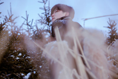 Low angle view of young man looking away during winter