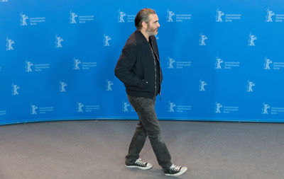 Full length of young man standing against blue wall