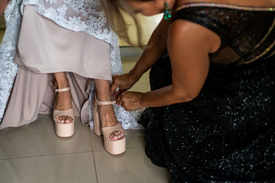 Bridesmaid adjusting bride sandal in wedding