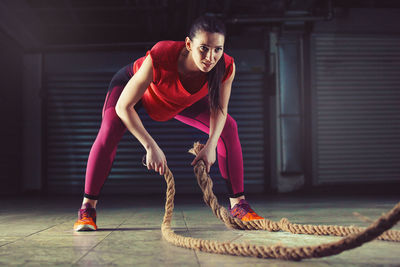 Young woman exercising with battle ropes 