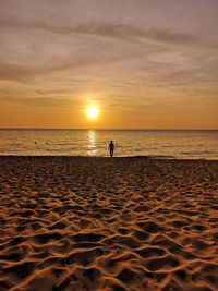 Silhouette person on beach against sky during sunset