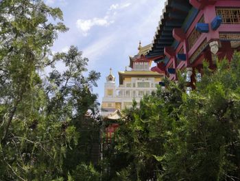 Low angle view of trees and buildings against sky