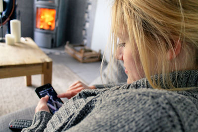 Side view of woman using smart phone while sitting on sofa at home