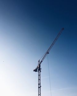 Low angle view of crane against clear blue sky