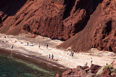 People on shore against rocks