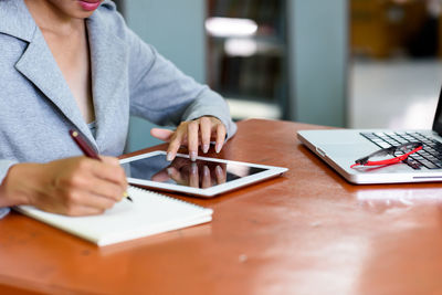 Midsection of man holding smart phone on table
