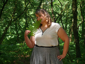 Beautiful young woman relaxing on tree trunk in forest