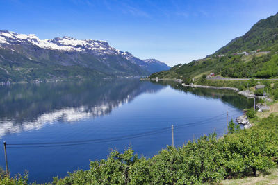 Scenic view of lake and mountains against blue sky