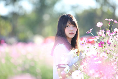 Side view portrait of beautiful young woman by flowering plants in park