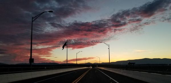 Cars on street against sky during sunset