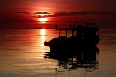 Silhouette boat in sea against sunset sky